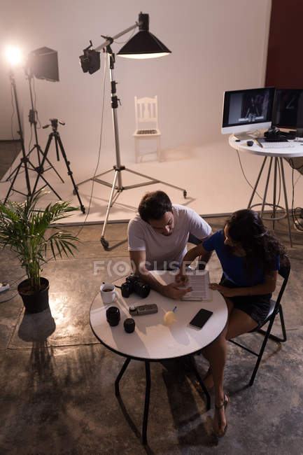 Photographe homme et mannequin femme écrivant sur presse-papiers en studio photo — Photo de stock