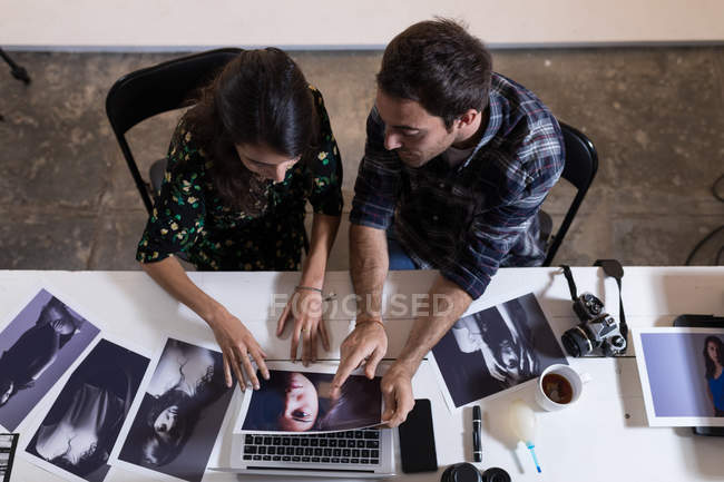 Male and female photographer discussing over photographs in photo studio — Stock Photo