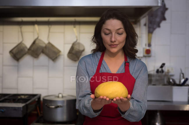 Female baker holding a proof dough in hand — Stock Photo