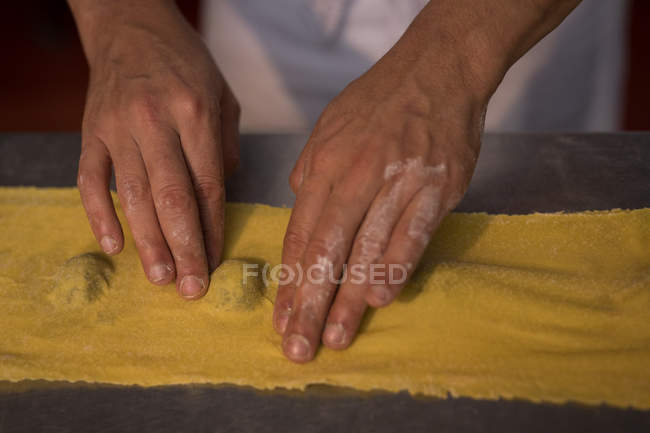 Primer plano del panadero masculino preparando pasta en la panadería - foto de stock