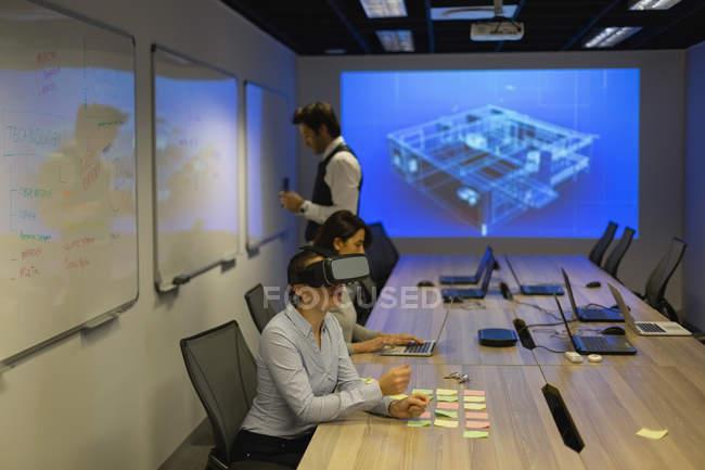 Бизнесвумен, использующая гарнитуру виртуальной реальности в конференц-зале в офисе — стоковое фото