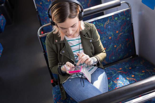 Young female commuter listening music while travelling in modern bus — Stock Photo