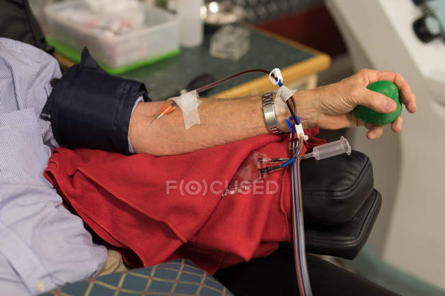 Mid section of senior man donating blood in blood bank — Stock Photo