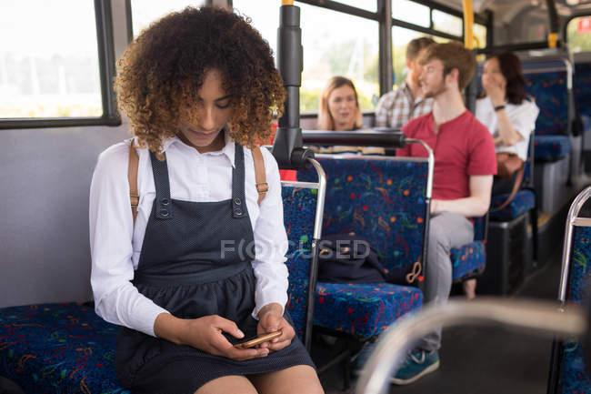 Viajeros femeninos jóvenes que utilizan el teléfono móvil mientras viajan en autobús moderno - foto de stock