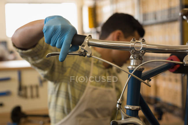 Primer plano del hombre examinando el freno de bicicleta en el taller - foto de stock