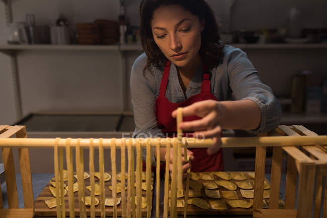 Panadero femenino preparando pasta en panadería - foto de stock