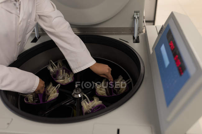 Laboratory technician placing blood bags in machine at blood bank — Stock Photo