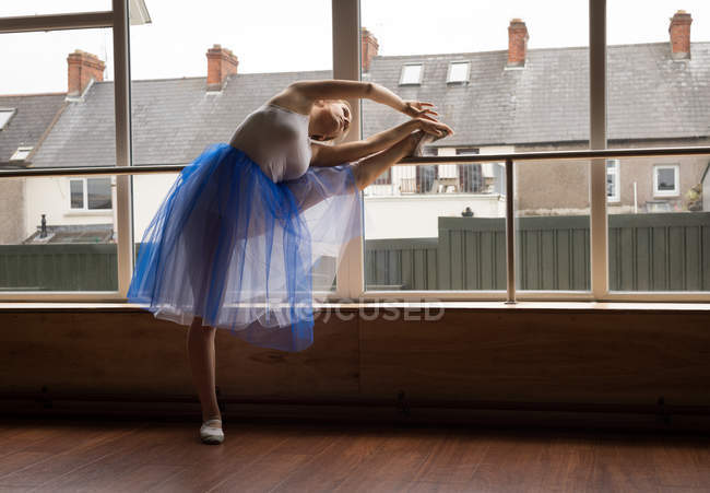 Bailarina practicando danza de ballet cerca de ventana en estudio de danza - foto de stock