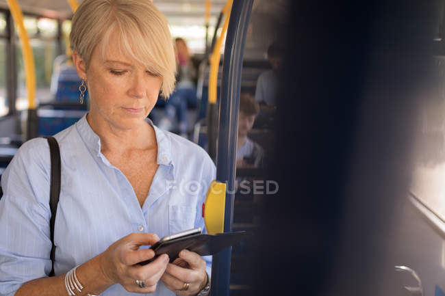 Viajante feminino usando telefone celular enquanto viaja em ônibus moderno — Fotografia de Stock