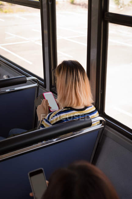Sobre la cabeza del viajero femenino utilizando el teléfono móvil mientras viaja en autobús moderno - foto de stock