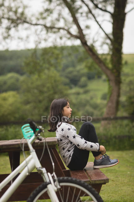 Jovem sentada no banco no jardim — Fotografia de Stock
