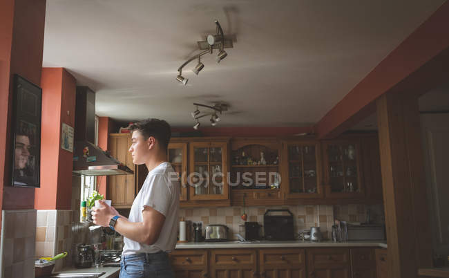 Чоловік має каву на кухні вдома, вид збоку . — стокове фото