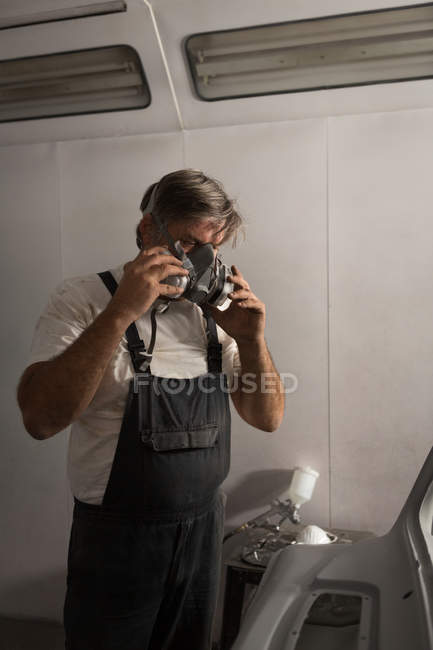 Mecânico masculino usando máscara de gás na garagem — Fotografia de Stock