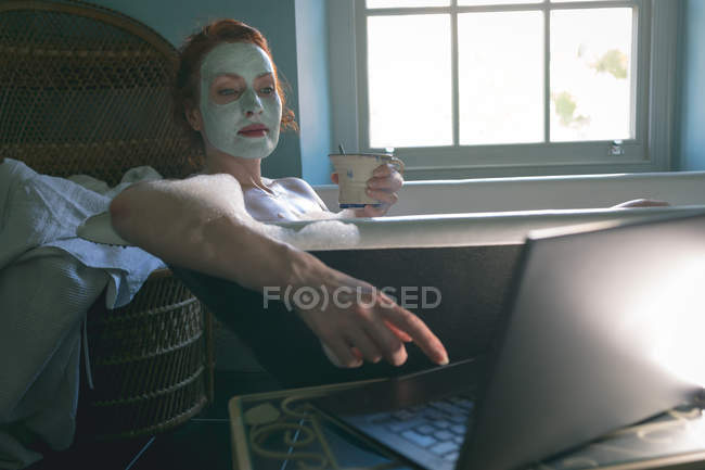 Frau benutzt Laptop in Badewanne im Badezimmer — Stockfoto