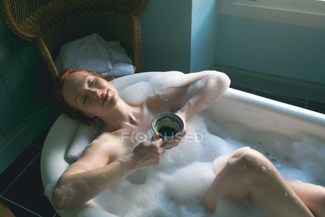 Mulher com xícara de café na banheira no banheiro — Fotografia de Stock