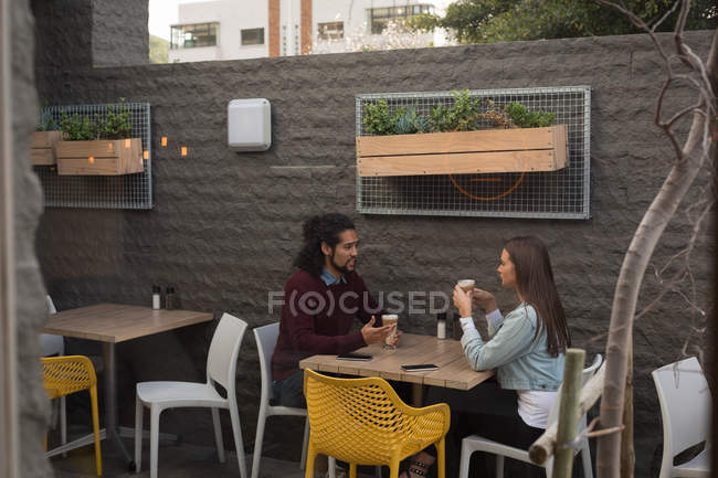 Casal jovem conversando uns com os outros no café ao ar livre — Fotografia de Stock