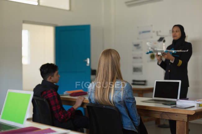 Pilota donna che insegna sui modelli di aereo ai bambini in istituto di formazione — Foto stock