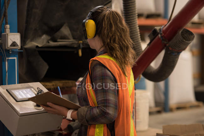 Travailleur féminin opérant la machine à l'entrepôt — Photo de stock