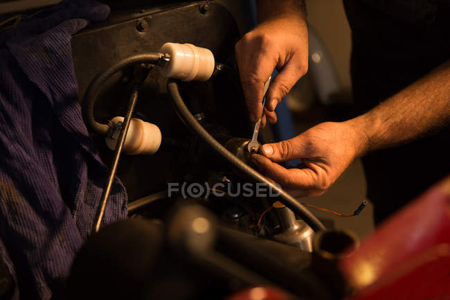 Мужской механик, обслуживающий автомобиль в гараже — стоковое фото