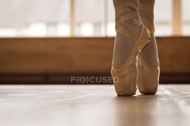Section basse de la ballerine dansant sur le plancher de bois dans le studio de danse — Photo de stock