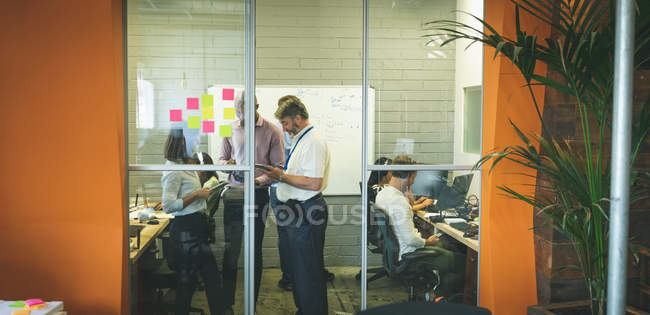 Деловые люди обсуждают за цифровым планшетом в офисе — стоковое фото
