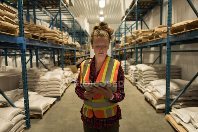 Travailleur féminin utilisant une tablette numérique à l'entrepôt — Photo de stock
