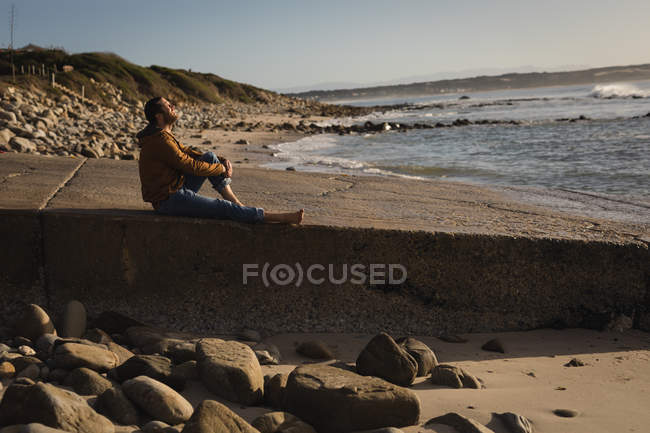 Продуманий чоловік сидить на набережній біля пляжу — стокове фото