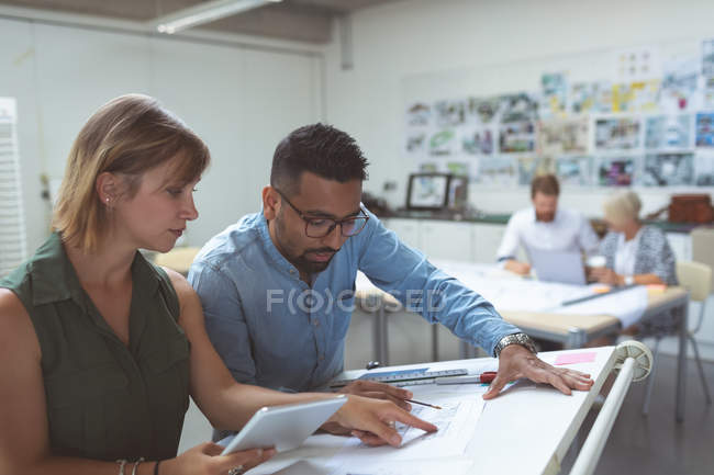 Executives discussing over blueprint on drafting table in office — Stock Photo