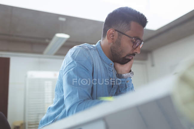 Thoughtful male executive working over drafting table in office — Stock Photo