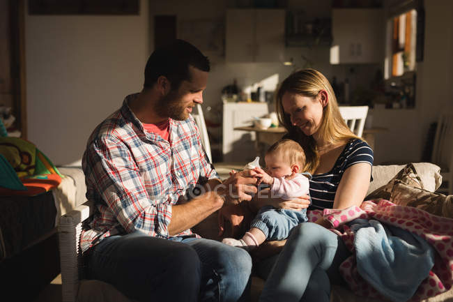 Parents having fun with baby on sofa at home — Stock Photo