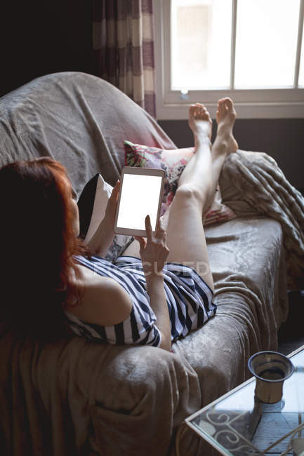 Vue arrière de la femme utilisant une tablette numérique à la maison — Photo de stock