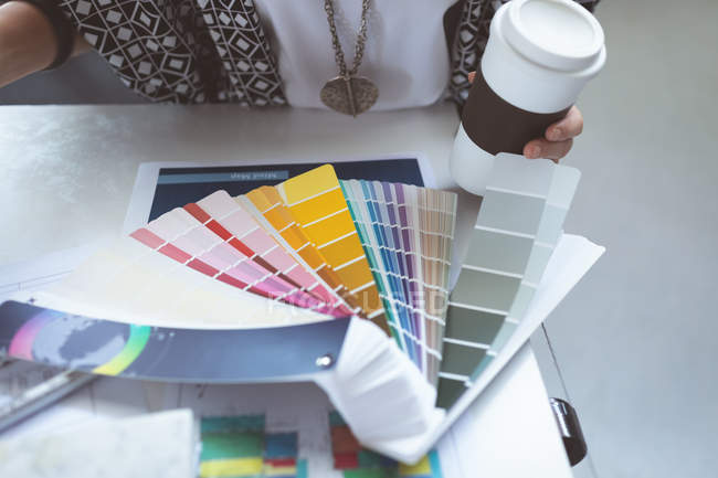 Крупный план женщины-руководителя, проверяющей цветные образцы на чертежном столе в офисе — стоковое фото