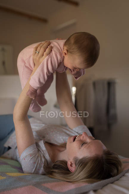 Mother having fun with baby on bed in bedroom at home — Stock Photo