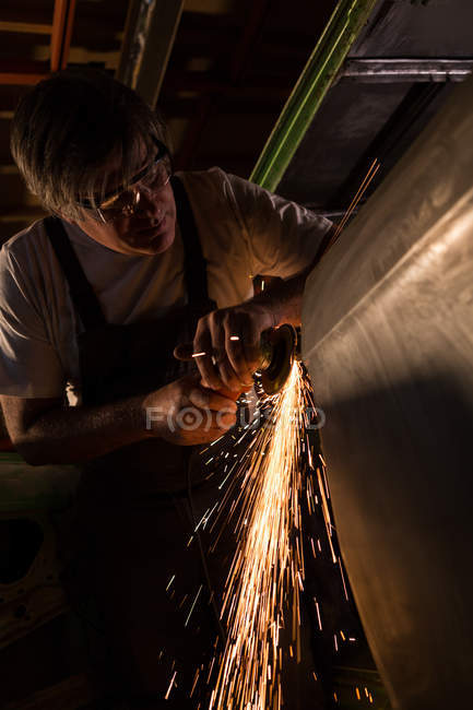 Mecánico masculino utilizando la máquina amoladora en el garaje - foto de stock