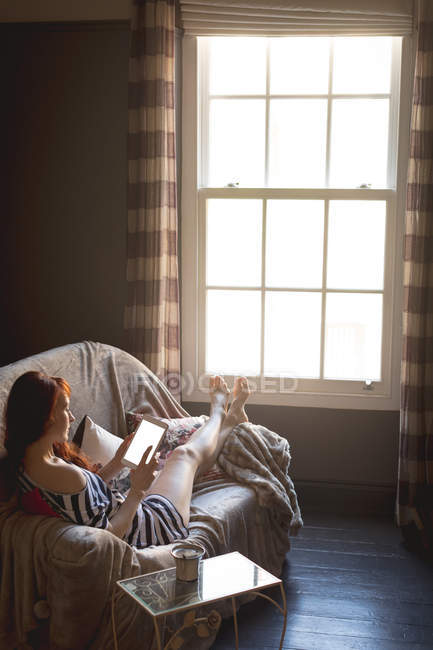 Frau nutzt digitales Tablet zu Hause auf Sofa — Stockfoto