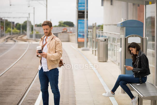 Пригородные с помощью мобильного телефона на платформе на железнодорожной станции — стоковое фото