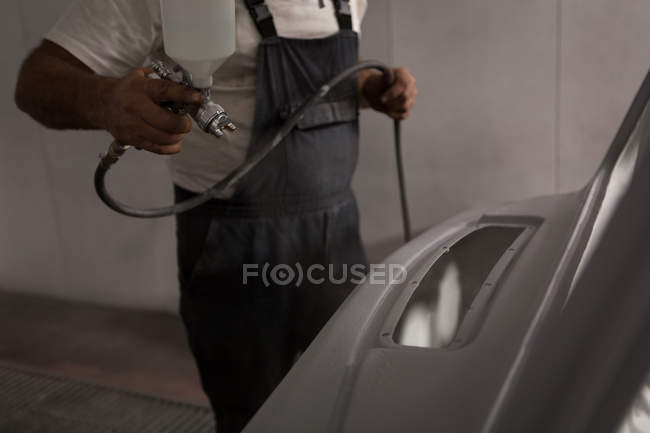 Мужской механик с использованием аэрозольной краски в гараже — стоковое фото