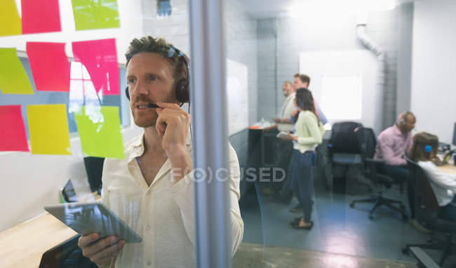 Ejecutivo masculino mirando notas adhesivas en la oficina - foto de stock
