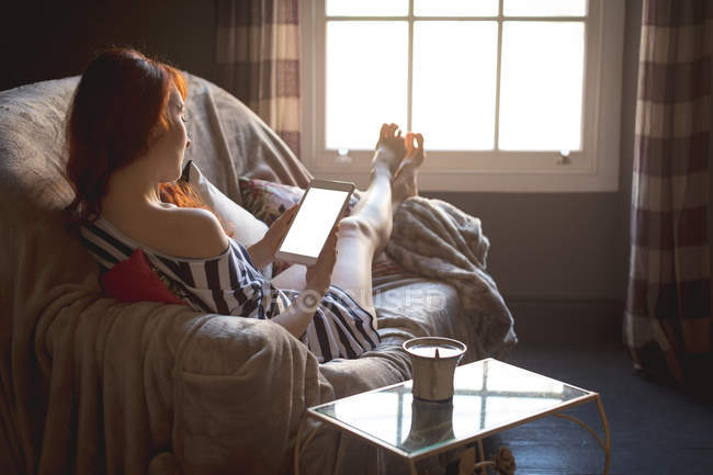 Frau nutzt digitales Tablet zu Hause auf Sofa — Stockfoto