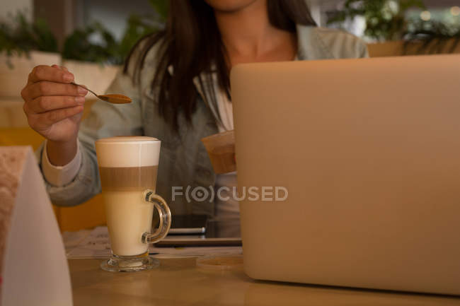 Metà sezione di donna che mette polvere di caffè in tazza di caffè in caffè — Foto stock
