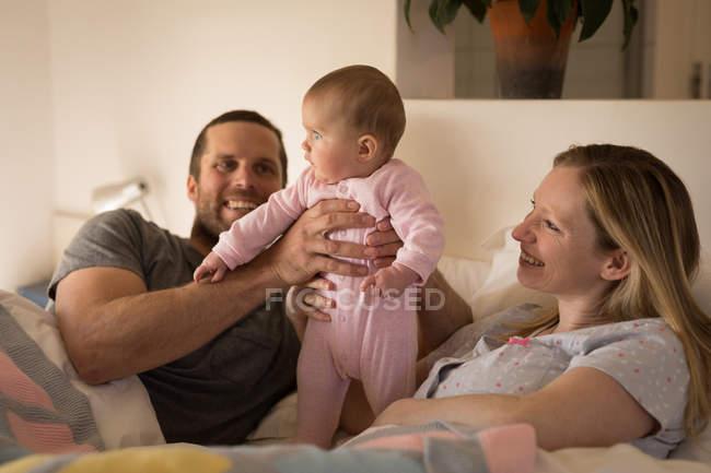 Os pais se divertindo com o bebê na cama em casa — Fotografia de Stock