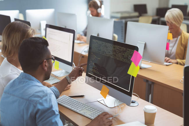 Executives discussing over desktop pc at desk in office — Stock Photo