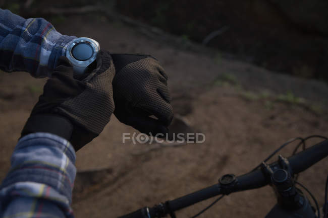 Man with bicycle using smartwatch at countryside — Stock Photo