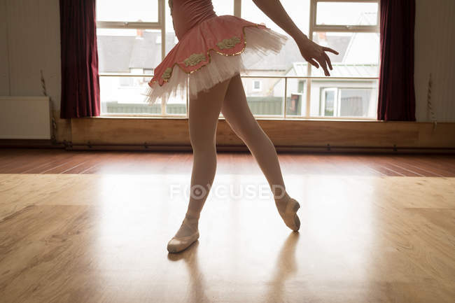 Sección media de bailarina bailando en piso de madera en estudio de danza - foto de stock