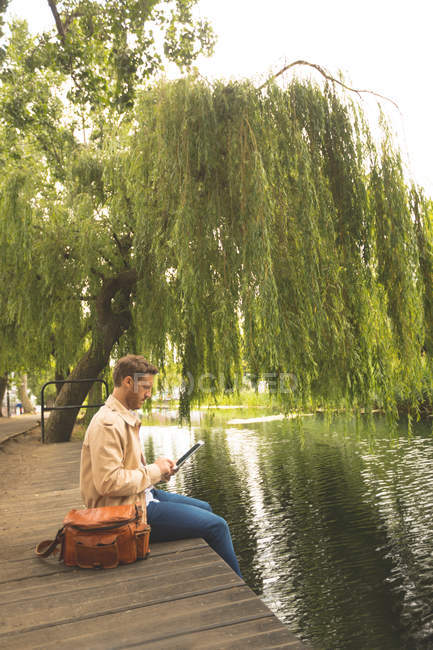 Вид збоку людини, що використовує цифровий планшет біля озера — стокове фото
