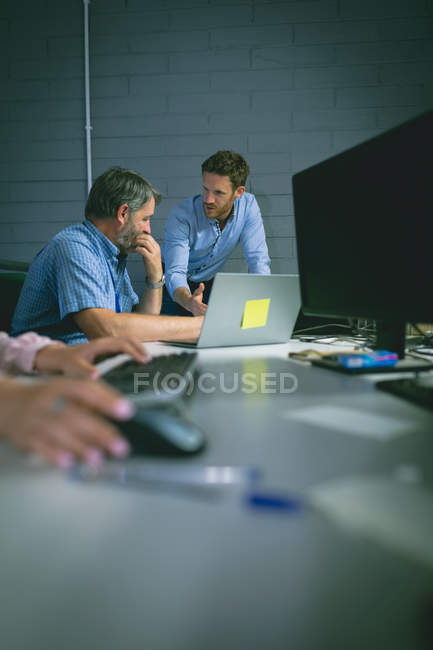 Деловые коллеги обсуждают за ноутбуком в офисе — стоковое фото