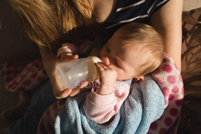 Крупный план матери, кормящей ребенка молоком на диване дома — стоковое фото