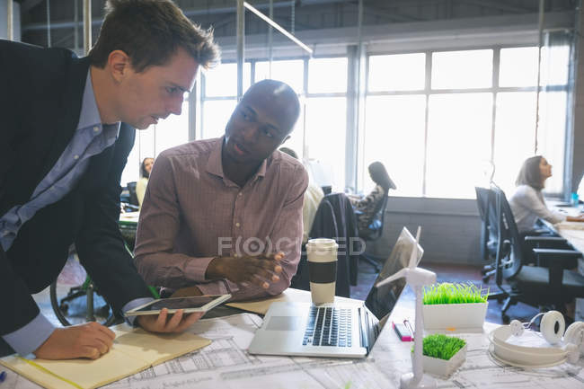 Бізнес-колеги обговорюють цифровий планшет в офісі — стокове фото