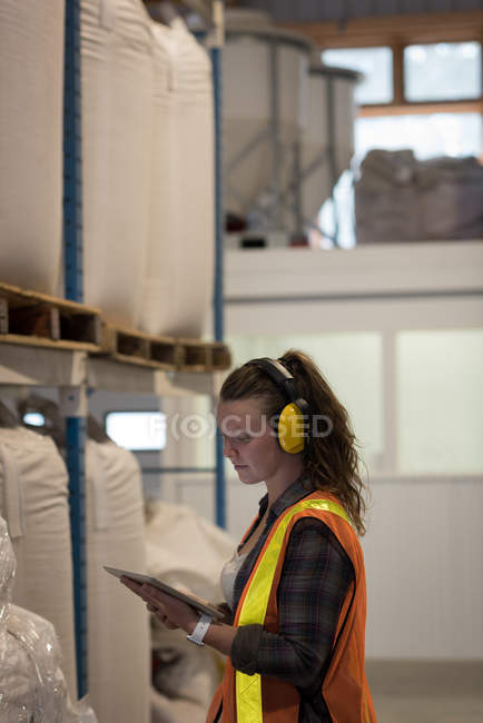 Trabalhadora feminina usando tablet digital em armazém — Fotografia de Stock