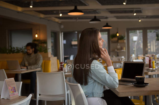 Giovane donna che parla al telefono cellulare in caffè — Foto stock